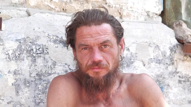 Homeless man looks at the camera and talks. Down-and-out person on the street. Real person with no fixed abode