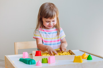 Little girl playing with colorful kinetic sand