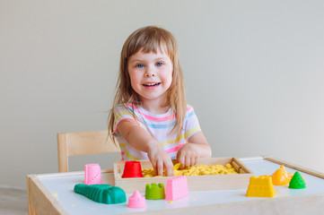 Little girl playing with colorful kinetic sand