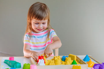 Smiling little girl playing with colorful kinetic sand