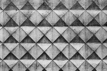 Part of a light concrete fence with rhombuses. White relief concrete wall with geometric shapes
