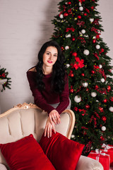  beautiful young brunette girl celebrates Christmas and New Year in a cozy house with Christmas tree gifts and garlands