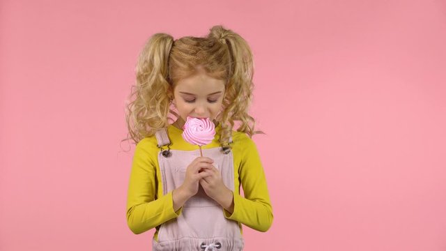 Pretty female child is eating a candy on the stick