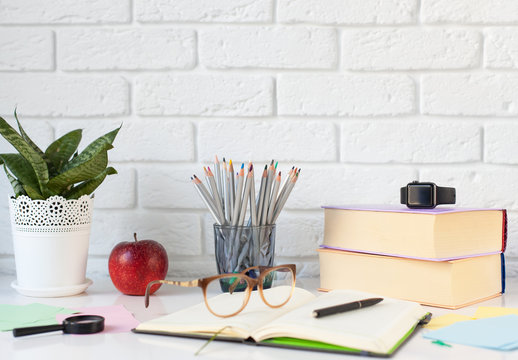 a desktop with books, a notebook, pencils and various school accessories against a white brick wall. interior, workflow. back to school, September 1 - Powered by Adobe