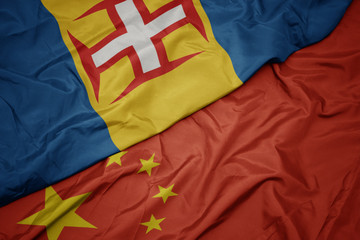 waving colorful flag of china and national flag of madeira.