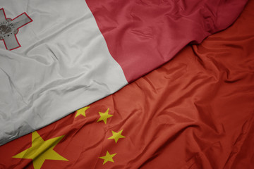 waving colorful flag of china and national flag of malta.