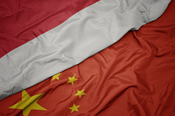 waving colorful flag of china and national flag of indonesia.