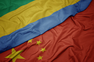 waving colorful flag of china and national flag of gabon.