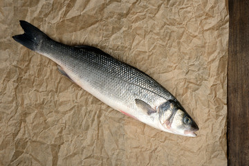 fresh whole sea bass fish on brown crumpled paper