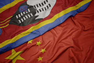 waving colorful flag of china and national flag of swaziland.