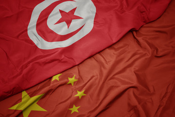 waving colorful flag of china and national flag of tunisia.