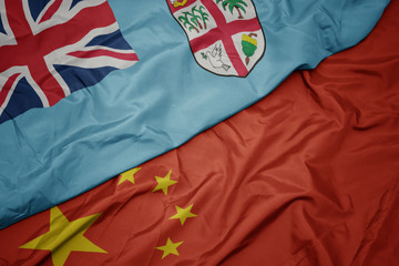 waving colorful flag of china and national flag of Fiji.