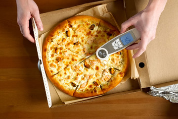 measuring pizza temperature with a thermometer