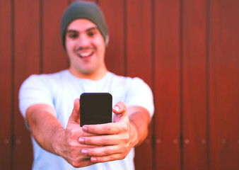 happy man making selfie on smartphone. Portrait of a cheerful man making selfie. Photo over brown wood background - Focus on finger-hands. Image
