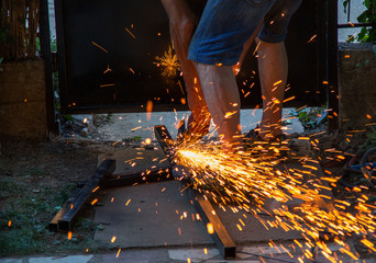 Worker craftsman cutting metal with grinder.