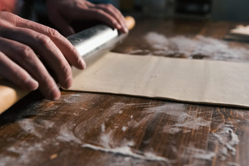 rolling out the dough with rolling pin on the table.