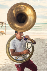 Musician man playing the tuba. Blowing hard as to make sound in that instrument