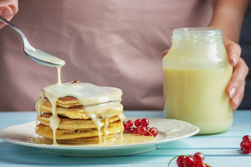 A girl in a pink apron adds condensed milk to pancakes. Delicious healthy food. Delicious pancakes...