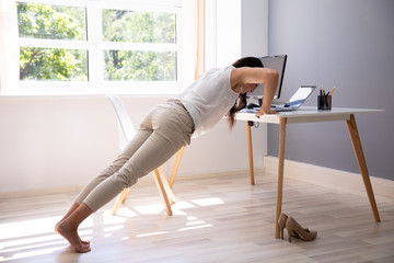 Businesswoman Doing Push Up On Office Desk