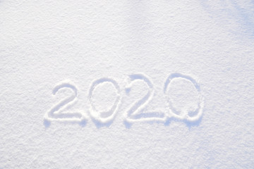 2020 text written on the background of fresh snow texture - winter holiday, Merry Christmas, New Year concept Sunny day, bright light with shadows. Greeting card with copy space for text.