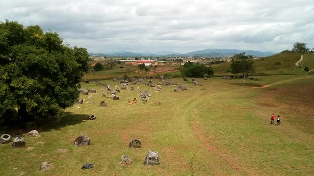 Aerial  panoramic view over Plain of Jars sites in Phonsavan, Laos Famous destination. Drone flying over millennia-old sandstone jars in green field. Day time with tourists.