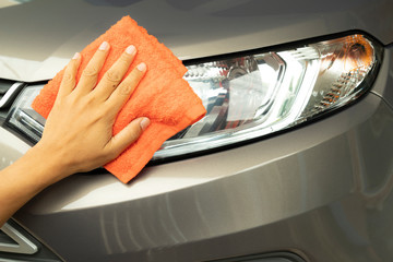 Hand cleaning car with orange micro-fiber cloth.
