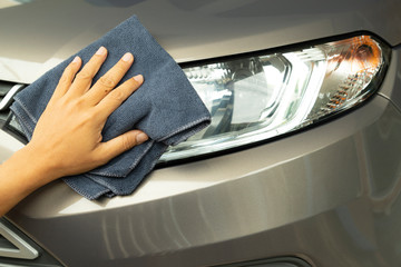 Hand cleaning car with blue micro-fiber cloth.
