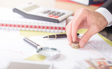 man is putting coins on stock market papers.financial background