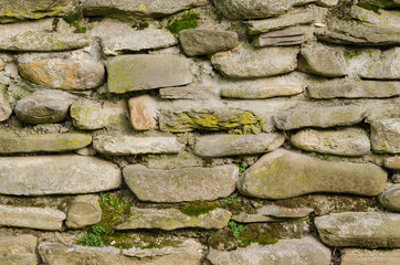 Old rustic stone brick wall with green moss, texture background