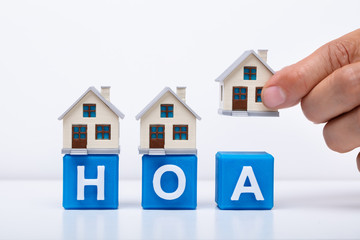 Businessman Placing House Models On HOA Cubic Blocks