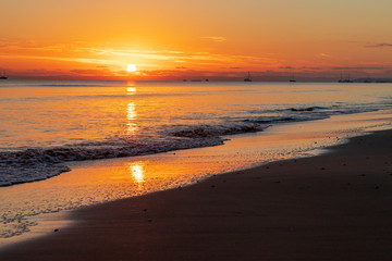 Fototapeta na wymiar Sun rising over ocean shore
