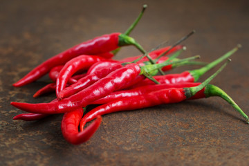Pods of hot red pepper on a rusty metal surface. 