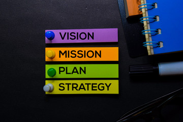 Vision, Mission, Plan, Strategy text on sticky notes isolated on Black desk. Mechanism Strategy Concept