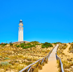 Fototapeta na wymiar Wooden walkway going to Faro de Trafalgar Lighthouse, in The Cabo de Trafalgar Cape Natural Park. Barbate, Los Caños de Meca, Cadiz. Andalusia, Spain.