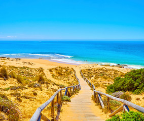 Wooden boardwalk going to Faro de Trafalgar Beach, a broad beach of The Cabo de Trafalgar Cape...