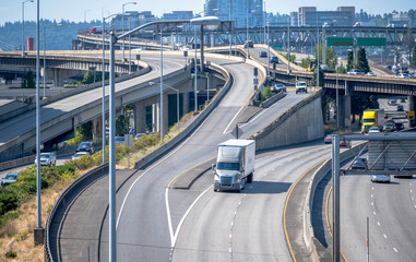 Big rig semi truck transporting commercial cargo running on the multi-level overpass highway...