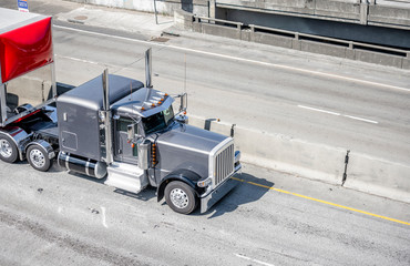 Classic shiny gray big rig semi truck with chrome details transporting cargo in covered semi...