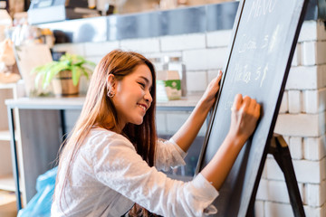 Professional Asian woman Barista writing menu front counter coffee shop occupation, part-time,job or owner business working woman happy selling and making drink beverage