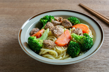 close up of stir fried japanese noodles with tuna and vegetables in a ceramic dish. homemade style food concept.