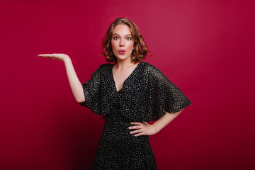 Indoor portrait of pleased young woman in beautiful black dress posing at home. Studio shot of...