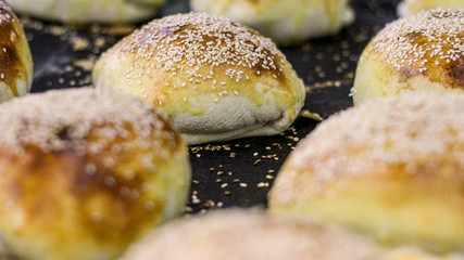 Some pizza breads with sesame dropped on a black tray