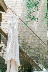 White Cream wedding dress hanging on stairs outside, modern lace wedding gown, copy space