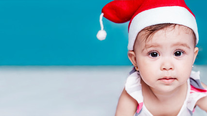 Little Santa. 1-year-old baby girl in Santa Claus hat. Merry Christmas. Adorable middle-eastern girl in Santa cap.