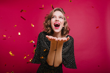 Lovable short-haired girl expressing positive emotions at party with confetti. Refined winsome lady...