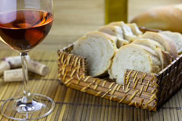 rose wine glass on table with basket of bread, olive oil and corks