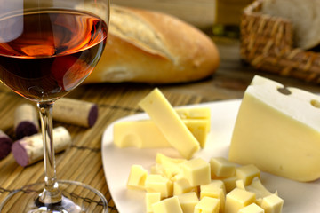 rose wine glass on wooden table with corks, breads, cheese board and olive oil