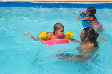 Father and his two daughters enjoys the pool on a hot summer day