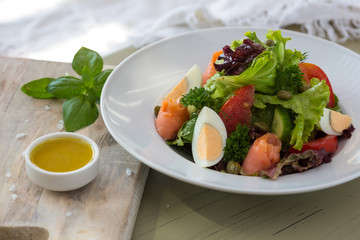 Vegetable salad with egg and salmon served with basil and topping sauce