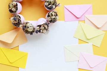 Colorful envelopes and Easter wreath on yellow background