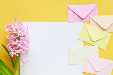 Colorful envelopes and hyacinth flowers on yellow background